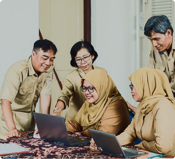 Tim guru berdiskusi menggunakan laptop